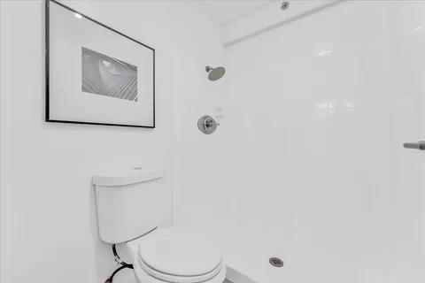 a white toilet sitting next to a white wall