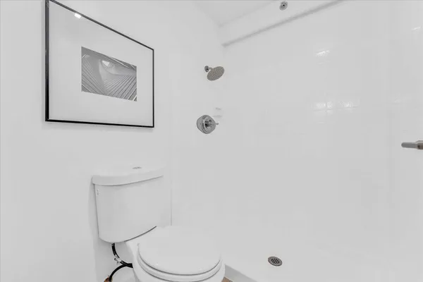 a white toilet sitting next to a white wall