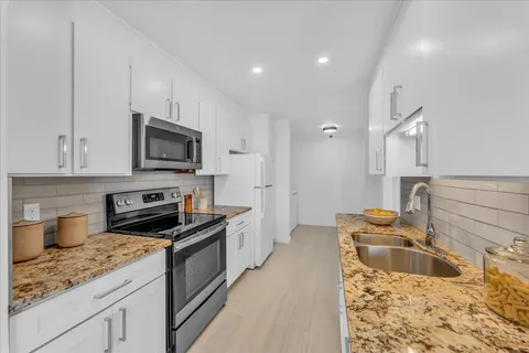 a kitchen with granite countertop a sink and steel appliances