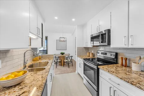 a kitchen with stainless steel appliances granite countertop a stove a sink and a microwave
