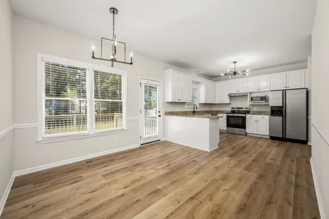 a view of kitchen with granite countertop stainless steel appliances a refrigerator cabinets and wooden floor