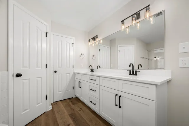 a spacious bathroom with a double vanity sink a mirror and shower