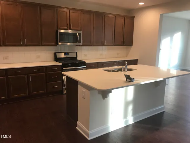 a kitchen with stainless steel appliances wooden cabinets a stove a sink and a microwave