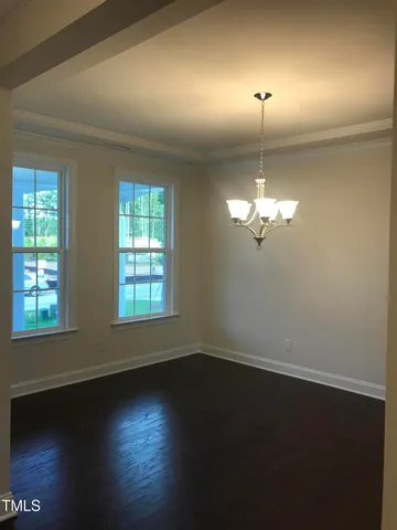 an empty room with wooden floor chandelier fan and windows