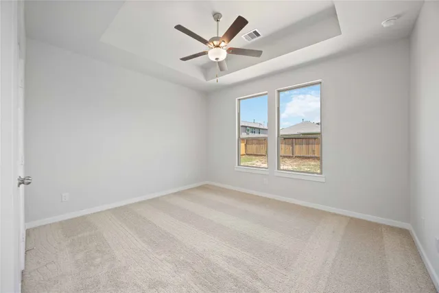 an empty room with windows and ceiling fan