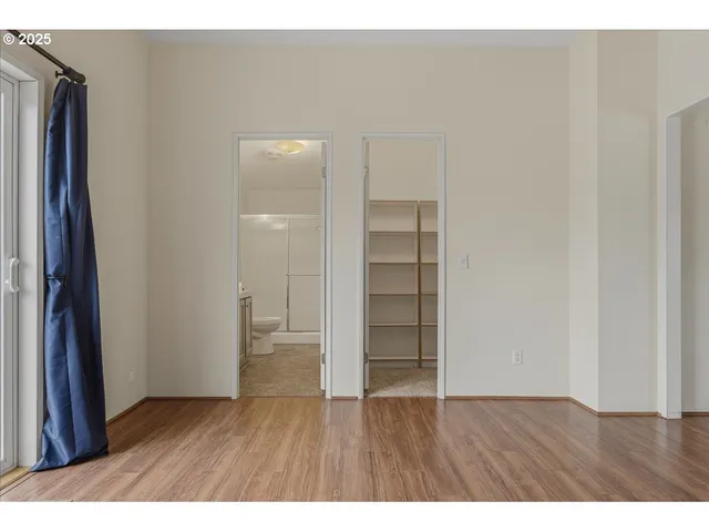 a view of an empty room with wooden floor and a bathroom