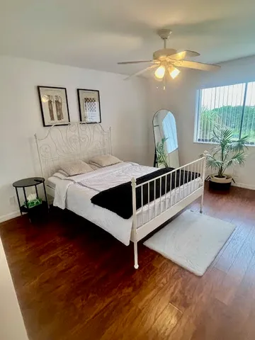 a view of a hallway to a livingroom with wooden floor and stairs
