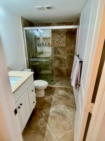 a bathroom with a granite countertop sink a toilet a mirror and shower