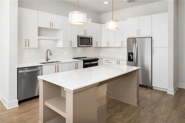 a kitchen with kitchen island white cabinets a sink a refrigerator and a stove