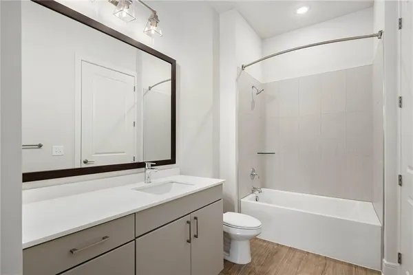 a bathroom with a bathtub shower sink vanity and toilet