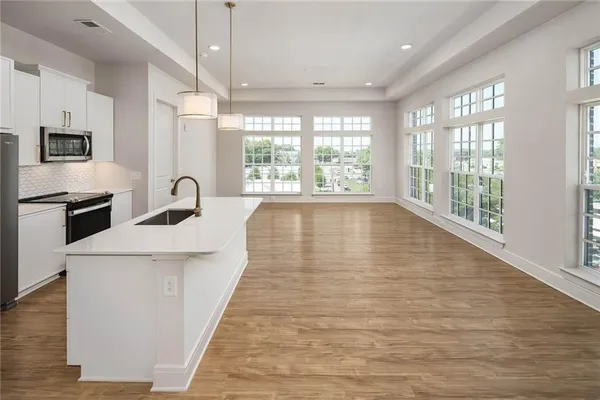 a large white kitchen with wooden floor and a large window