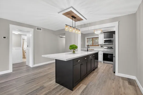 a kitchen with kitchen island granite countertop a sink cabinets and wooden floor