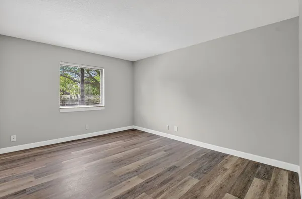 a view of an empty room with wooden floor and closet