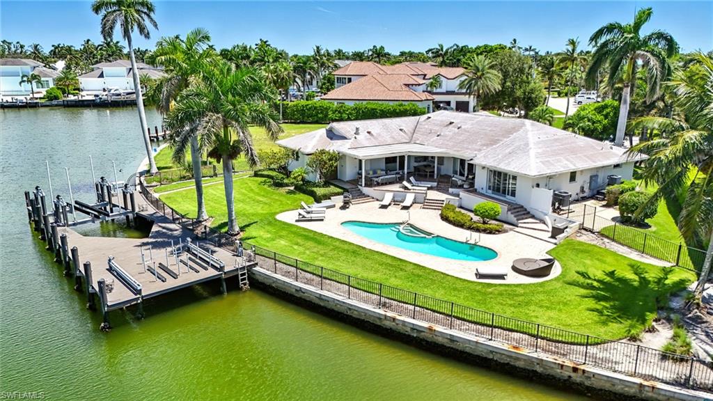 an aerial view of a house with swimming pool lawn chairs and lake view