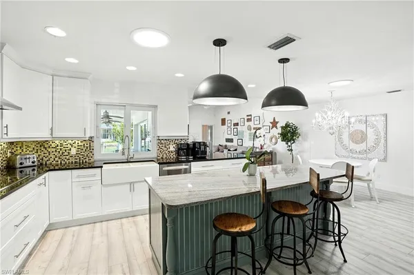 a kitchen with stainless steel appliances a dining table chairs and white cabinets