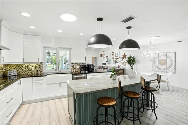 a kitchen with stainless steel appliances a dining table chairs and white cabinets