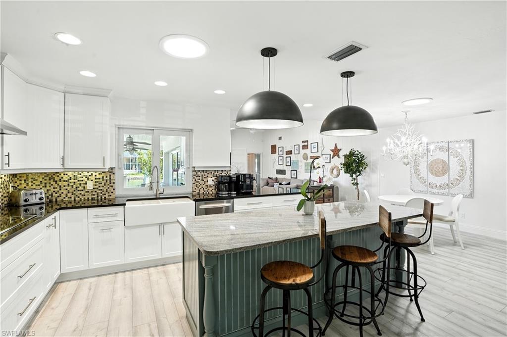 205 Springline Drive Naples, FL 34102 - Photo 5 of 26 a kitchen with stainless steel appliances a dining table chairs and white cabinets