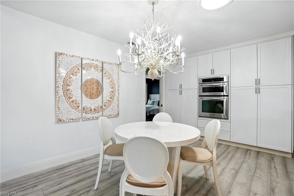 205 Springline Drive Naples, FL 34102 - Photo 7 of 26 a dining room with furniture a chandelier and wooden floor