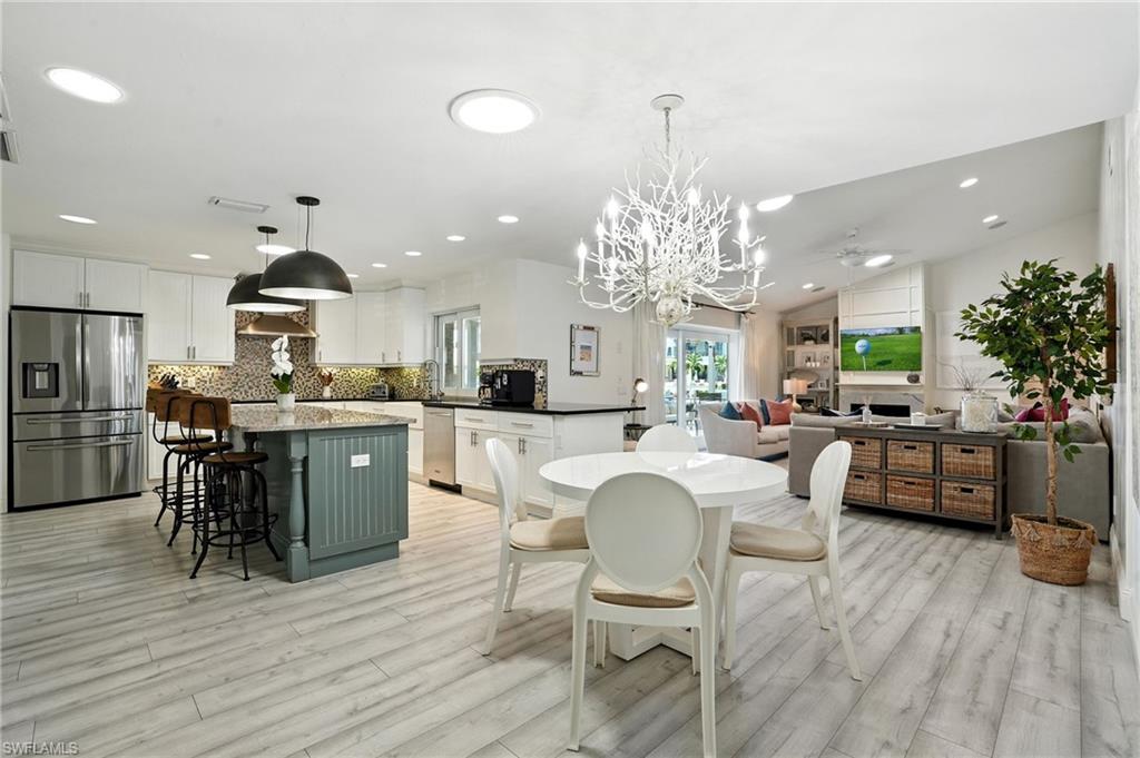 205 Springline Drive Naples, FL 34102 - Photo 8 of 26 a kitchen with stainless steel appliances kitchen island granite countertop a refrigerator a stove a dining table and chairs with wooden floor