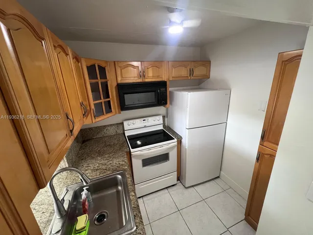 a kitchen with stainless steel appliances granite countertop a refrigerator a stove and a sink