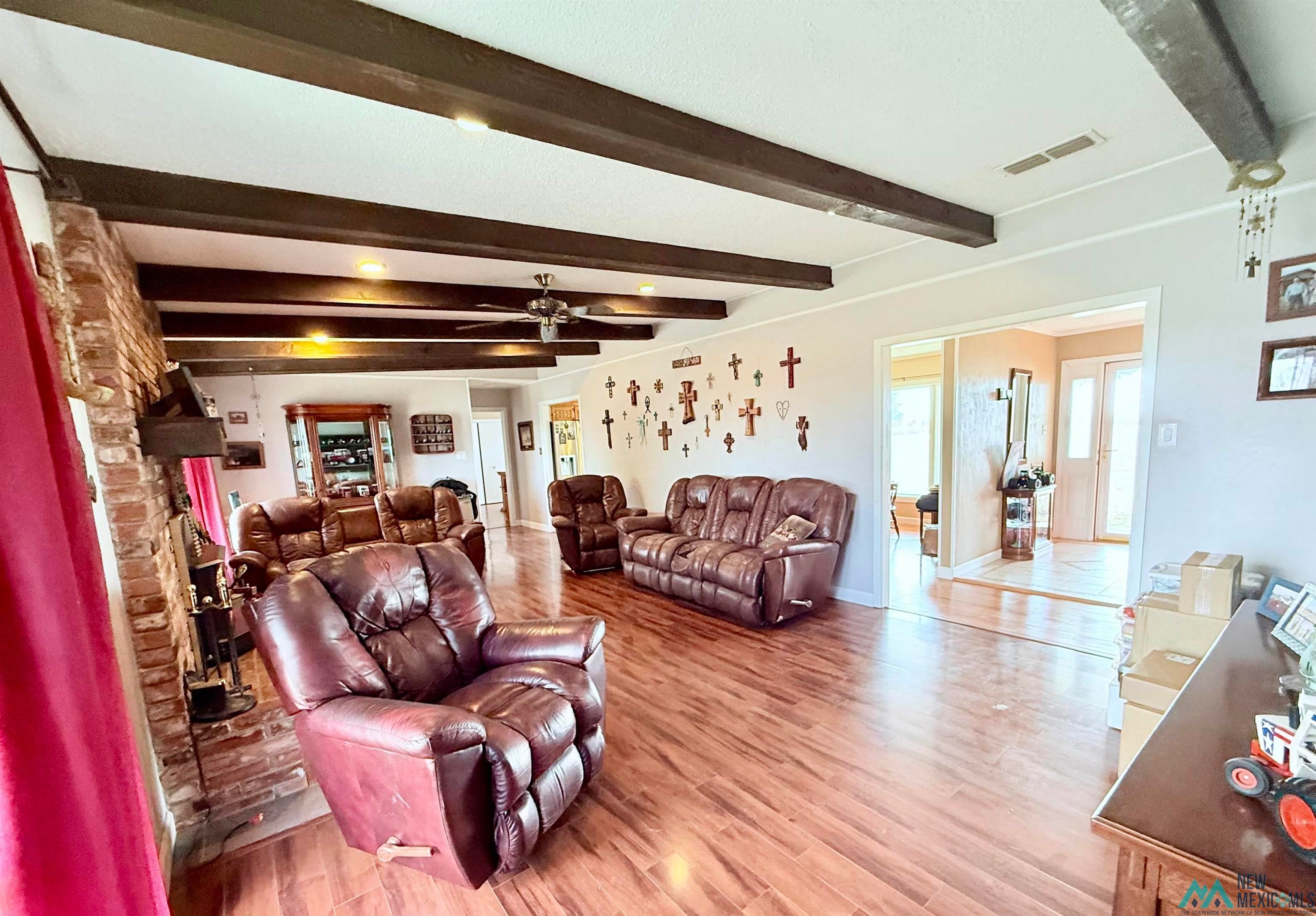 997 State Rte 108 Texico, NM 88135 - Photo 12 of 33 Spacious living area featuring exposed wood beams, recessed lighting, wood-finish flooring, and a brick-faced fireplace