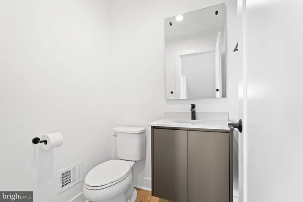a bathroom with a toilet a sink a mirror and vanity