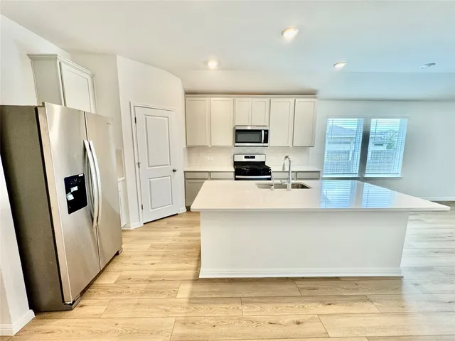 a large kitchen with stainless steel appliances a refrigerator a stove a sink a washer dryer and a cabinets