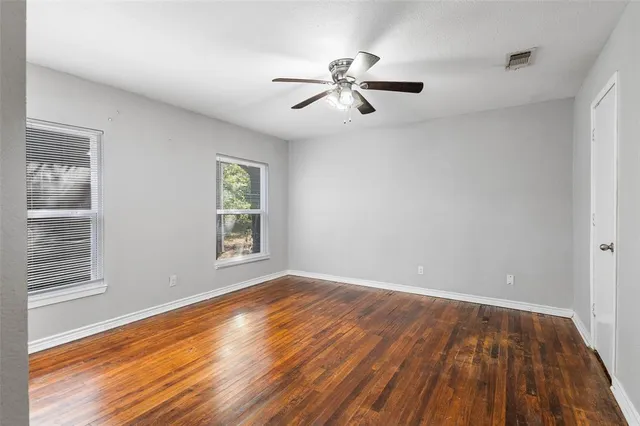 a view of empty room with wooden floor and fan