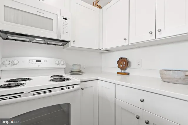 a kitchen with white cabinets and white appliances