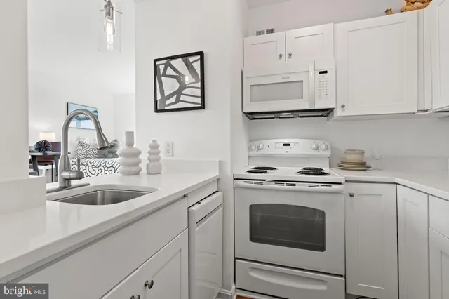 a kitchen with granite countertop white cabinets and white appliances