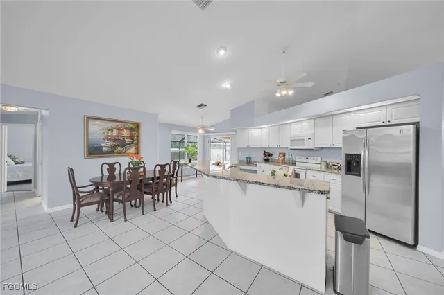 a kitchen with stainless steel appliances granite countertop a refrigerator and a dining table