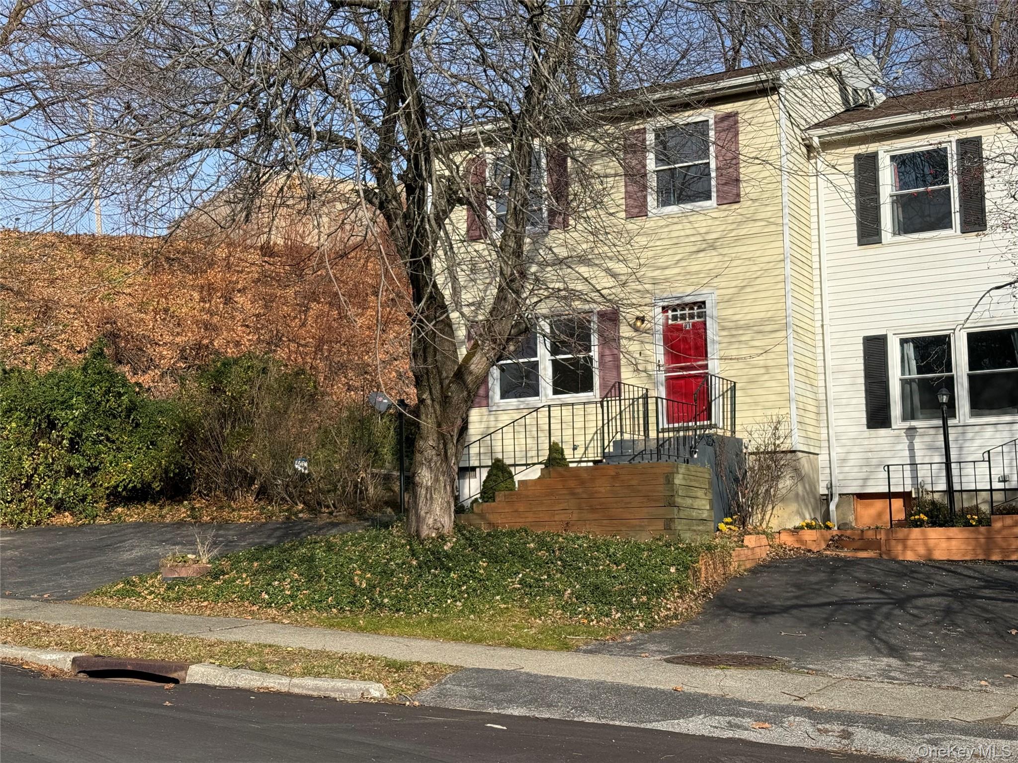 a view of a white house with large tree and wooden fence