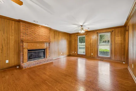 a view of an empty room with window and wooden floor