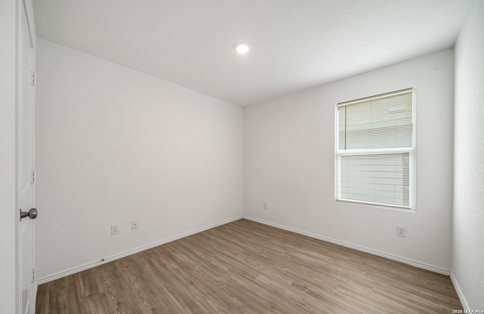 6566 Runaway Row Converse, TX 78109 - Photo 17 of 27 a view of an empty room with wooden floor and a window