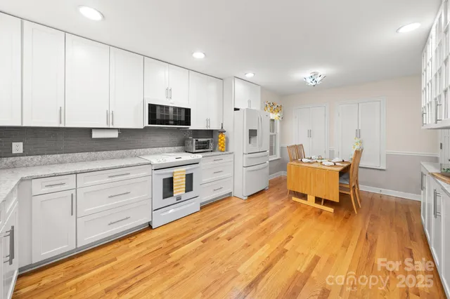 a kitchen with stainless steel appliances kitchen island granite countertop a stove a sink and white cabinets