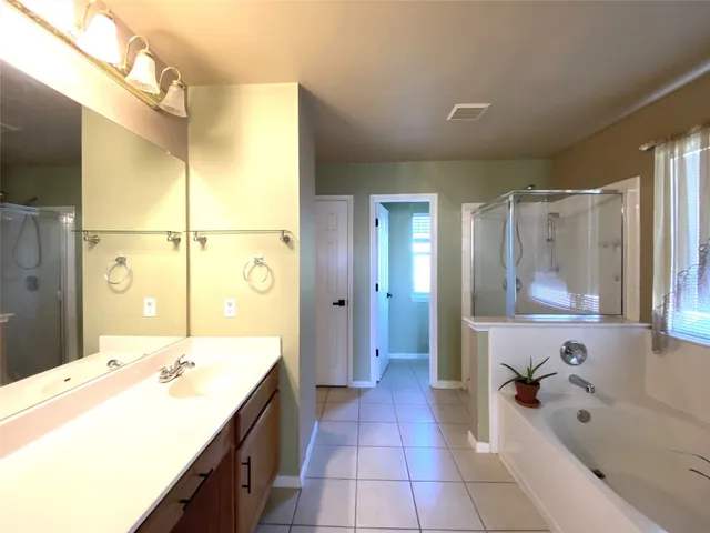 a spacious bathroom with a tub sink shower and mirror