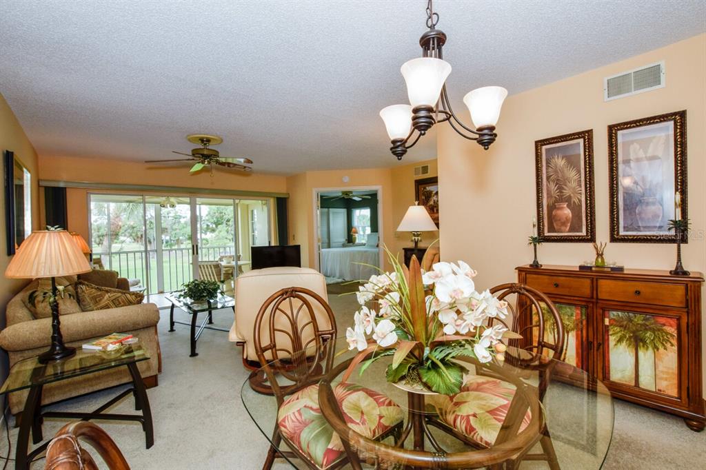 433 Cerromar Lane, Unit 438 Venice, FL 34293 - Photo 6 of 44 a living room with furniture chandelier and large windows