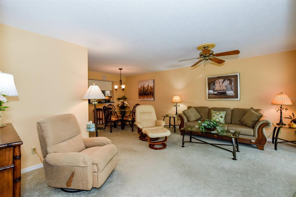 433 Cerromar Lane, Unit 438 Venice, FL 34293 - Photo 8 of 44 a living room with furniture and a chandelier