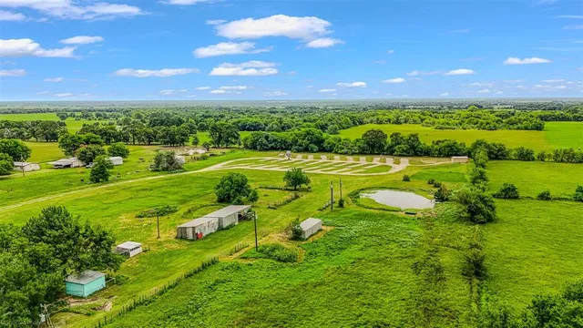 a view of a white house with a big yard and large trees