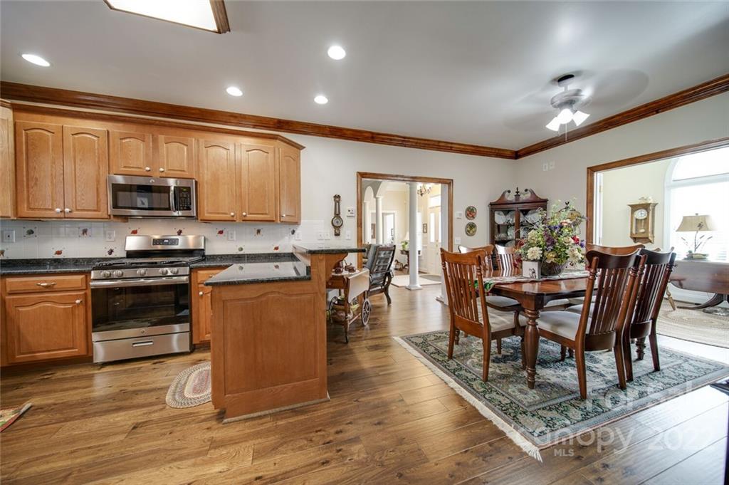 155 St Peters Church Road Gold Hill, NC 28071 - Photo 18 of 47 a kitchen with stainless steel appliances granite countertop a stove a sink a microwave a dining table and chairs with wooden floor