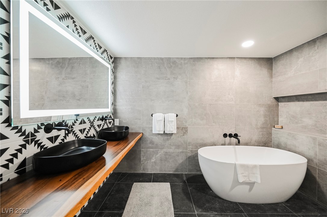 1640 Crystal Shadows Circle Las Vegas, NV 89119 - Photo 18 of 44 Full bath with tile walls, a freestanding bath, dark tile patterned flooring, recessed lighting, and double vanity