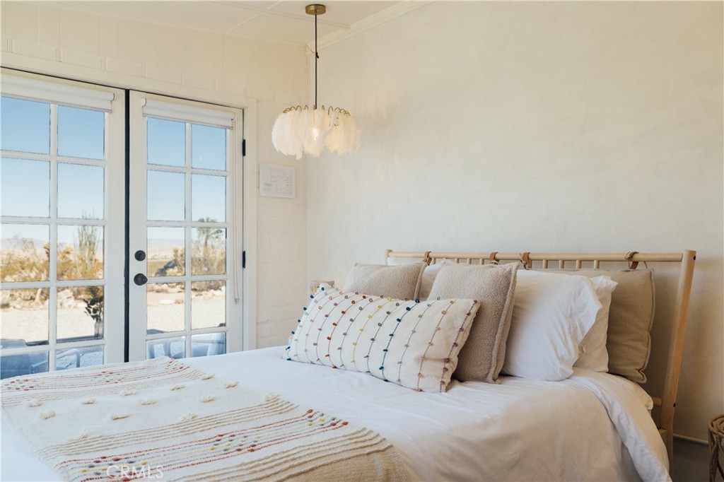 75243 Sullivan Road Twentynine Palms, CA 92277 - Photo 21 of 62 a bedroom with a large bed and a chandelier