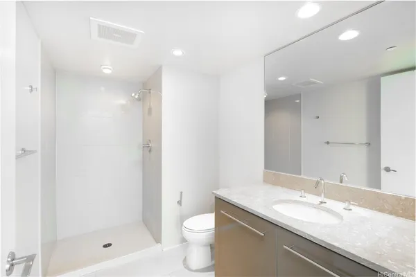 a bathroom with a granite countertop sink a toilet and shower