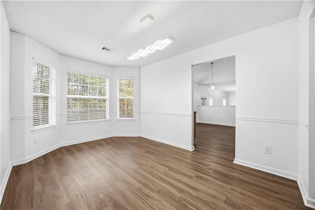a view of empty room with wooden floor and windows