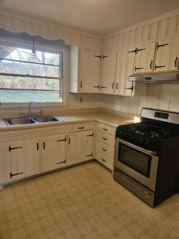 a view of kitchen and empty room with wooden floor