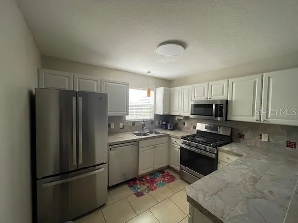 a kitchen with stainless steel appliances granite countertop a refrigerator stove and microwave