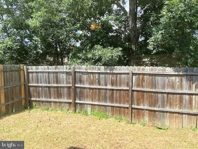 a backyard of a house with a large tree and wooden fence