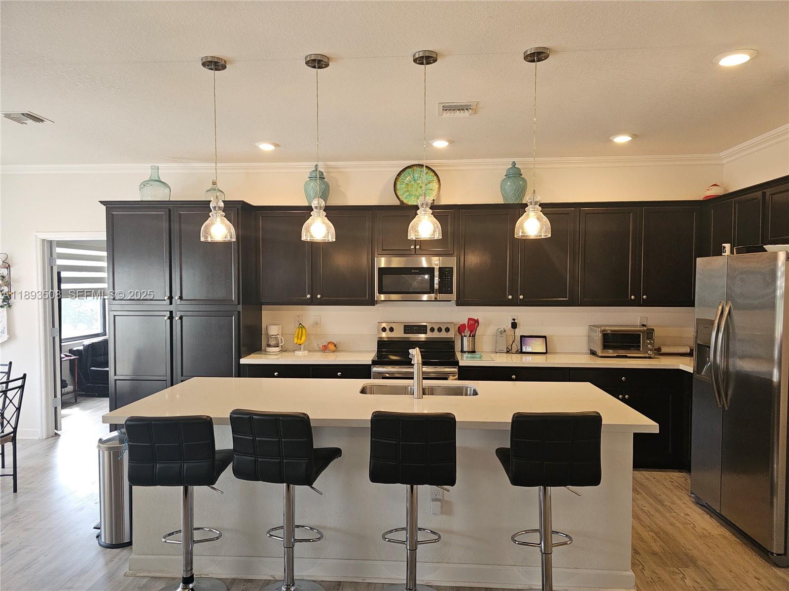 18964 Southwest 135th Avenue Miami, FL 33177 - Photo 15 of 39 a kitchen with stainless steel appliances kitchen island granite countertop a dining table and chairs
