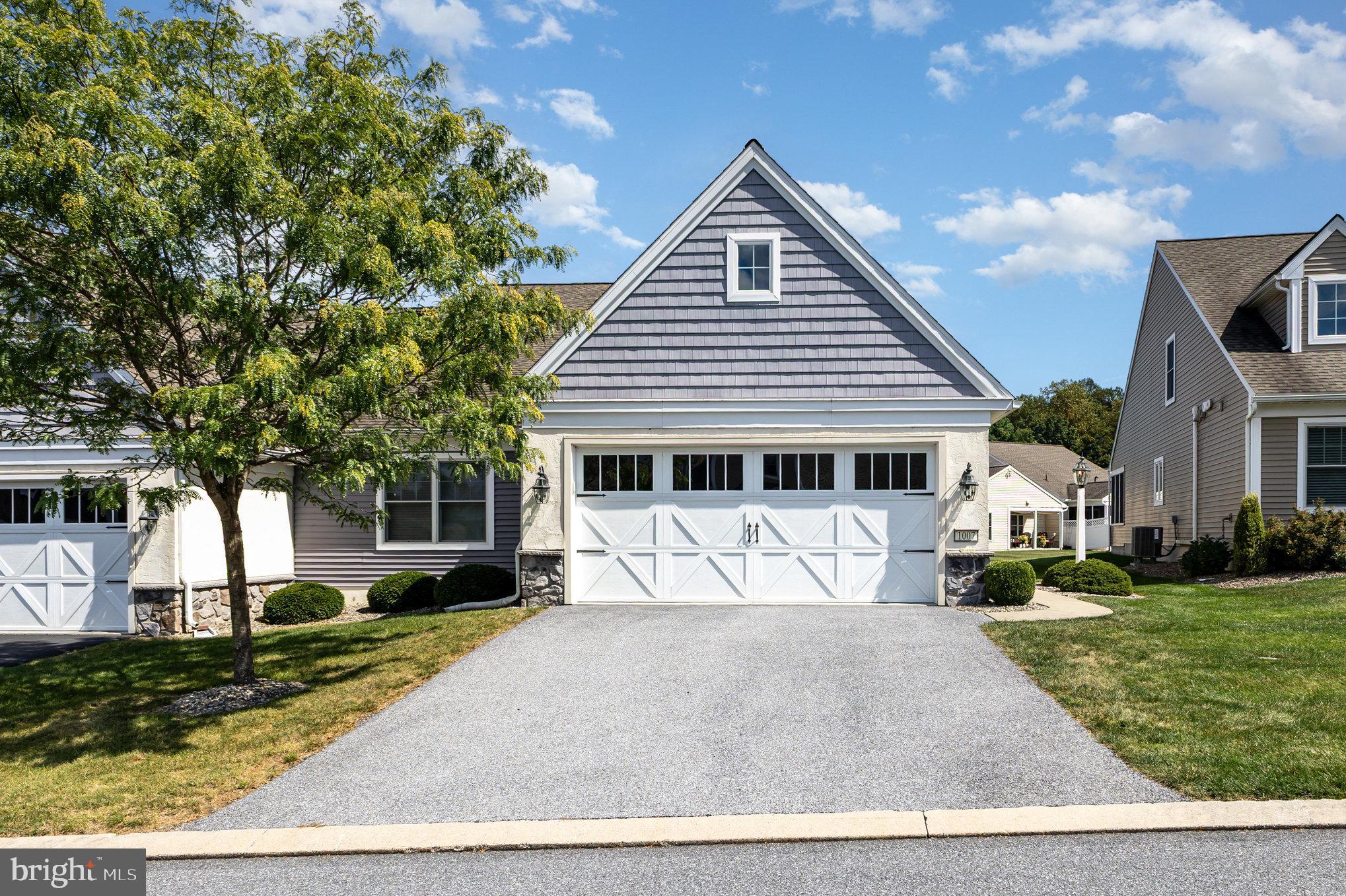 a front view of a house with a yard outdoor seating and covered with trees