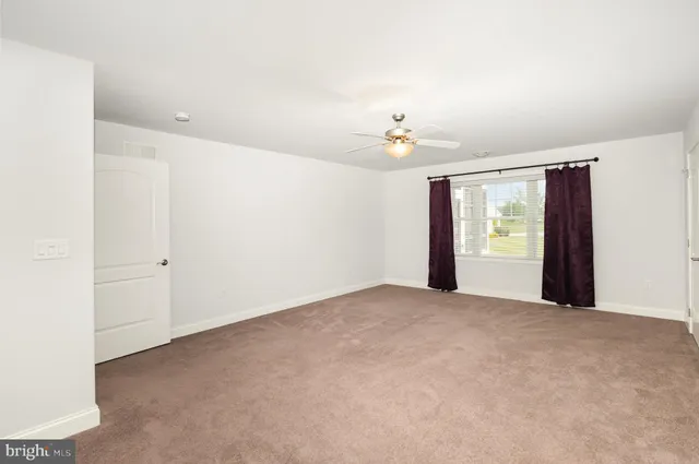 an empty room with chandelier fan and windows